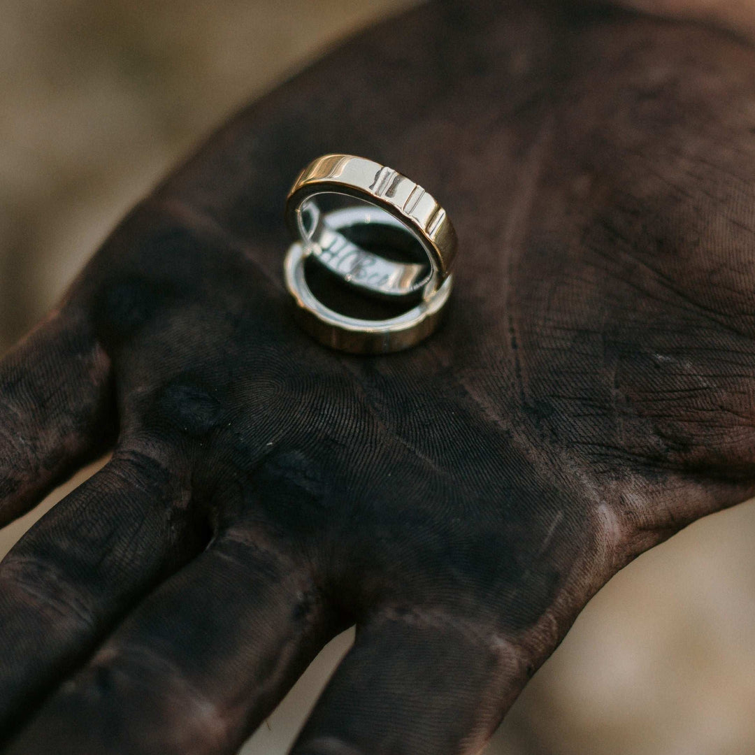 Hells Canyon Stamped Metal Wedding Bands Held in Hand