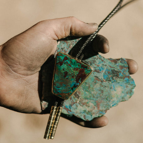 Capture the essence of the Southwest with our Chrysocolla Bolo Tie, radiating deep blue and turquoise hues. This stunning accessory embodies the spirit of the desert landscape, showcasing intricate patterns and vibrant colors. Elevate your look with a touch of Southwestern charm and undeniable style.