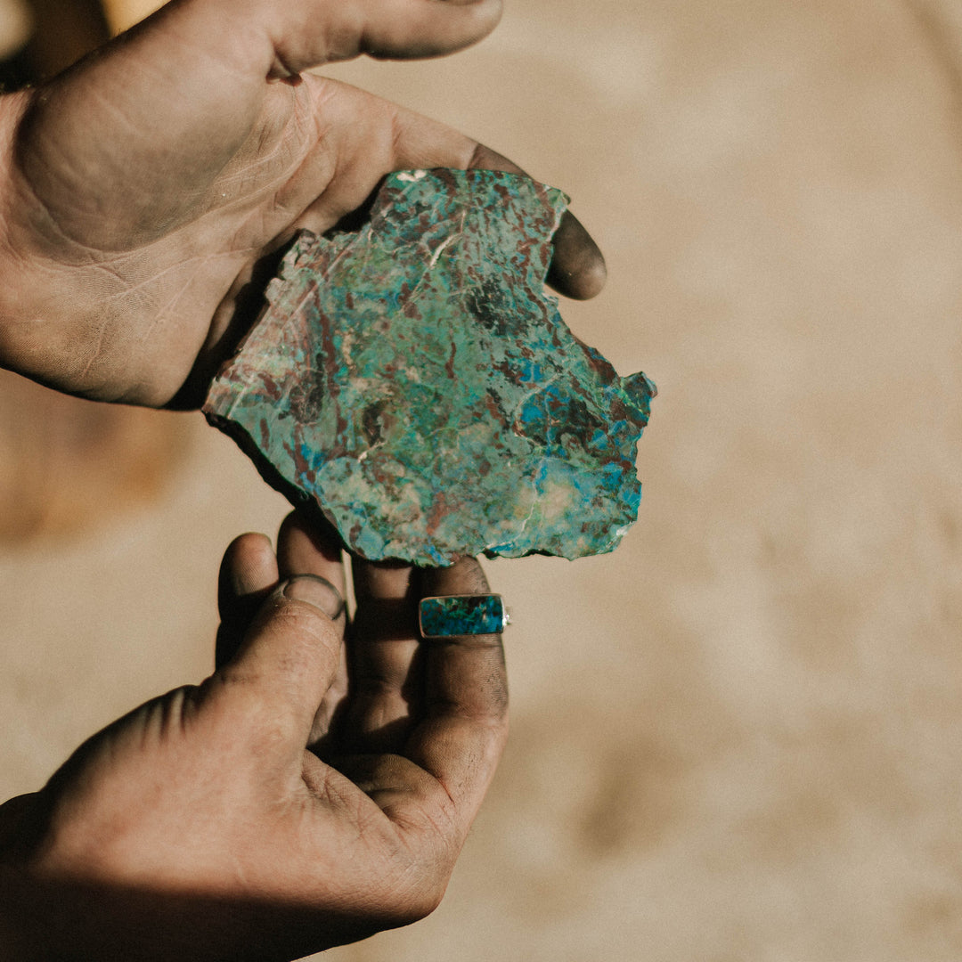Chrysocolla Ring on Finger of Hand Holding Slab
