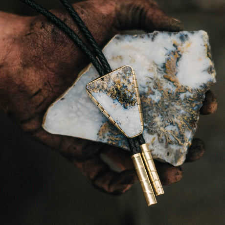 Discover the enchanting charm of our Graveyard Point Plume Agate Bolo Tie, sourced from Idaho and embodying Western elegance. This captivating accessory showcases the unique beauty of the region with its mesmerizing patterns and vibrant hues. Elevate your ensemble with a touch of natural splendor and timeless Western style, courtesy of this exquisite bolo tie.