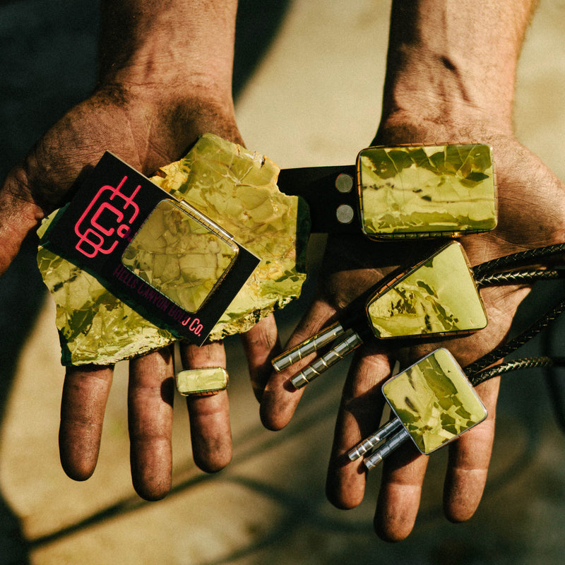 Hands holding Cactus Green Morrisonite bolo ties, money clips,rings and belt buckle