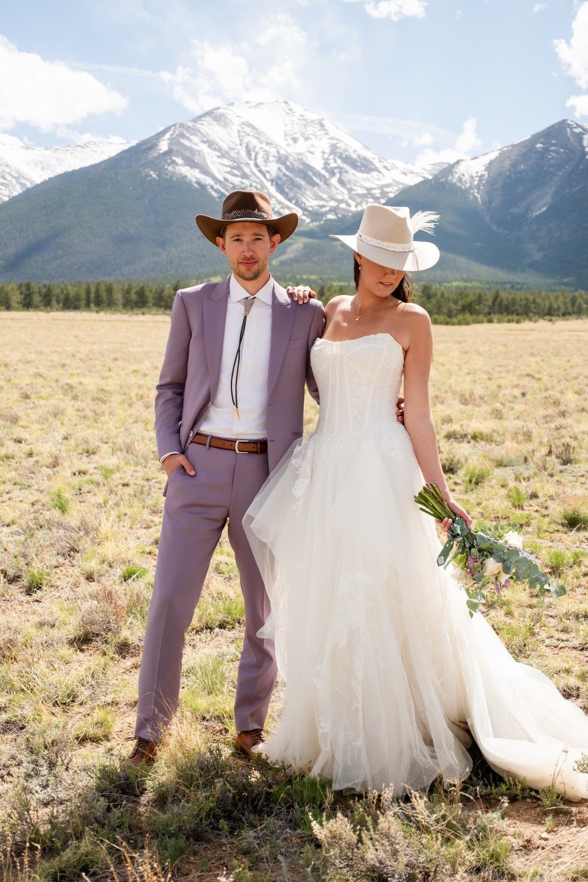 Bride and groom wearing a wedding bolo tie in front of mountain scenery, western rustic wedding style