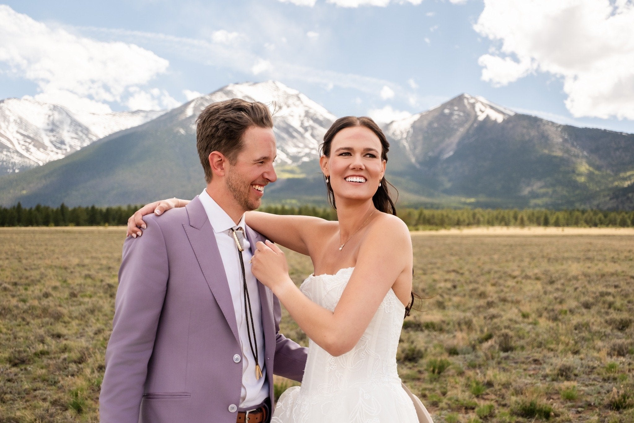 Smiling couple on their wedding day with groom wearing a bolo tie, outdoor mountain wedding photography