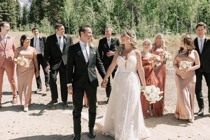 Wedding party with bride and groom wearing bolo tiewalking outdoors in a forest setting